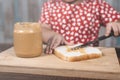 Little asian girl spreading a peanut butter on a white bread.