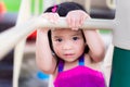 Little Asian girl wasn`t sure to try hanging on the bar. Children want to play but are afraid of falling.