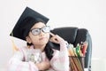 Little Asian girl wearing graduate hat hugging clear glass jar piggy bank and smile with happiness for money saving to wealthness Royalty Free Stock Photo