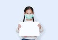 Little asian girl wearing protective mask with showing blank white paper on white background. Child holding empty white copy space Royalty Free Stock Photo