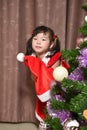 a little Asian girl wearing a Santa Claus costume with christmas tree for the Christmas festival and new year celebration Royalty Free Stock Photo