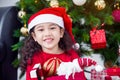 Girl wearing santa hat and smiles while opening christmas gift at home Royalty Free Stock Photo