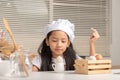 A little Asian girl wearing a white chef hat is staring at a duck egg on a small jug Royalty Free Stock Photo