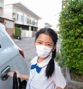 A little Asian girl wears a uniform and a mask