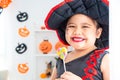 Girl in witch dress smiling and holding candy .