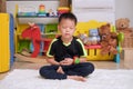 Little Asian kid with eyes closed, barefoot practices yoga, meditating to relieve negative emotions