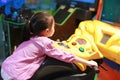 Little Asian kid girl playing arcade video game. Motorcycle Racing