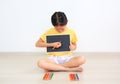 Little asian kid girl sitting indoor holding blackboard and use color pencil drawing on blank board Royalty Free Stock Photo