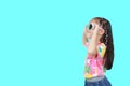 Little Asian kid girl wearing a flowers summer dress and sunglasses looking up isolated on cyan background with copy space. Summer Royalty Free Stock Photo