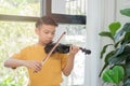 A Little Asian kid playing and practice violin musical string instrument against in home, Concept of Musical education, Royalty Free Stock Photo