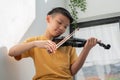 A Little Asian kid playing and practice violin musical string instrument against in home, Concept of Musical education, Royalty Free Stock Photo