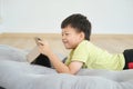 Little Asian kindergarten boy child lying on his stomach while using tablet pc, Gadget addicted kid