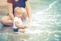 Little Asian 10 months baby excited playing the beach first time. Mother closely take care baby while playing the water