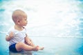 Little Asian 10 months baby excited playing the beach first time. Baby sitting along the beach