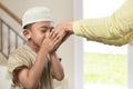 Little asian muslim boy with traditional dress kissing parents h Royalty Free Stock Photo