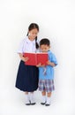 Little Asian school boy and girl in Thai school uniform standing with reading book isolated on white background. Full length Royalty Free Stock Photo