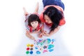 Little asian (thai) girl painting with her mother near by, on white background. Studio shot. Top view Royalty Free Stock Photo