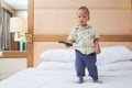 Little Asian toddler baby boy child holding the tv remote control and watching television in bedroom Royalty Free Stock Photo