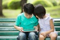 Little Asianboy and girl are playing together with a computer ta