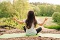 Little athletic girl sitting on sporty rug and practicing yoga in front of river. Active kid meditating in nature.