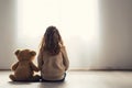 Little autistic girl with teddy bear sitting on floor at empty room. Autism concept Royalty Free Stock Photo