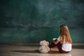 Little girl with teddy bear sitting on floor in empty room. Autism concept Royalty Free Stock Photo