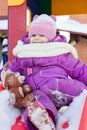 Little babe girl playing on the winter playground. Royalty Free Stock Photo