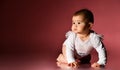 Little babe in a smart white bodysuit with inscription, barefoot. She is creeping on the floor against pink background. Close up Royalty Free Stock Photo