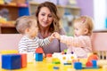 Little babies playing with Montessori toy in pre-school, creche or kindergarten