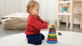 Little baby assembling to tower or pyramid on the floor at home. Baby development, child playing games, education and learning Royalty Free Stock Photo