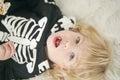 Little baby with blond hair enjoy sweets in halloween costume