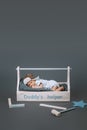 little baby in bodysuit lying in wooden toolkit with daddys helper lettering and hammer