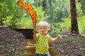 Little baby boy carrying giant fallen leaf walk in park