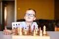 Little baby boy with down syndrome with big blue glasses playing chess in kindergarten Royalty Free Stock Photo