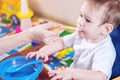 Little baby boy eating on a chair in the kitchen. Mom feeds holding in hand a spoon of porridge