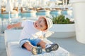 Little baby boy in a hat sitting on a background of the pool and