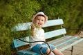Little baby boy in a hat sitting on a bench and smiling in the s Royalty Free Stock Photo