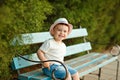 Little baby boy in a hat sitting on a bench and smiling in the s Royalty Free Stock Photo