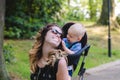 Mom spends time with her little son. He wears it in a baby carrier. I walk in the park and smile. Royalty Free Stock Photo