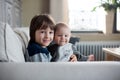 Little baby boy and his older brother, sitting on a couch in sun Royalty Free Stock Photo