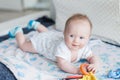 Little baby boy 3 months old lies on his stomach on the sofa in a bright room, the child smiles Royalty Free Stock Photo