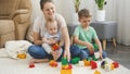 Little baby boy and older brother playing with mother in toys on carpet in living room. Concept of family having time Royalty Free Stock Photo