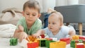 Little baby boy with older brother playing toy blocks and bricks on carpet in living room. Concept of children Royalty Free Stock Photo