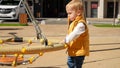 Little baby boy playing outdoor on the playground with nest rope swing. Children playing outdoor, kids outside, summer holiday and Royalty Free Stock Photo