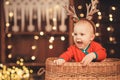 Little baby boy in reindeer antlers sitting in a wicker basket Royalty Free Stock Photo