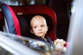 Little baby boy sitting in the car seat in the car.