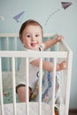 Little baby boy standing in his crib in light room