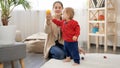Little baby boy taking colorful toys from his mother and walking on soft carpet in living room. Baby development, family playing Royalty Free Stock Photo