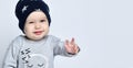 Little baby boy toddler in grey casual jumpsuit, black cap with starssmiling and gesticulating Royalty Free Stock Photo