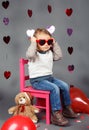 Little baby boy toddler sitting on small pink chair with bear toy in studio wearing red funny glasses Royalty Free Stock Photo